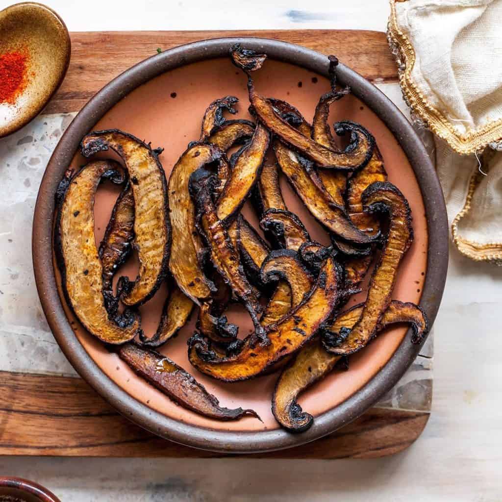 slices of mushroom jerky on a plate on top of a wooden cutting board