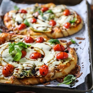 Top shot of small pizza made on naan and topped with mozzarella cheese and tomatoes.