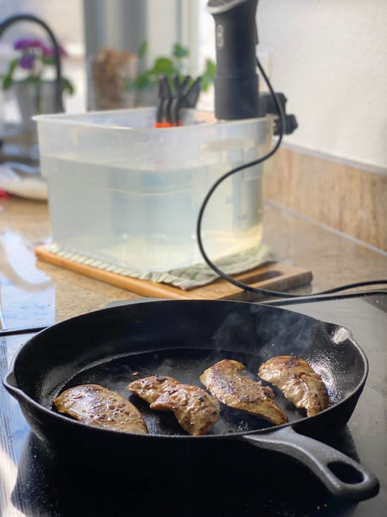 keto friendly sous vide chicken in a cast iron pan with anova sous vide machine in background