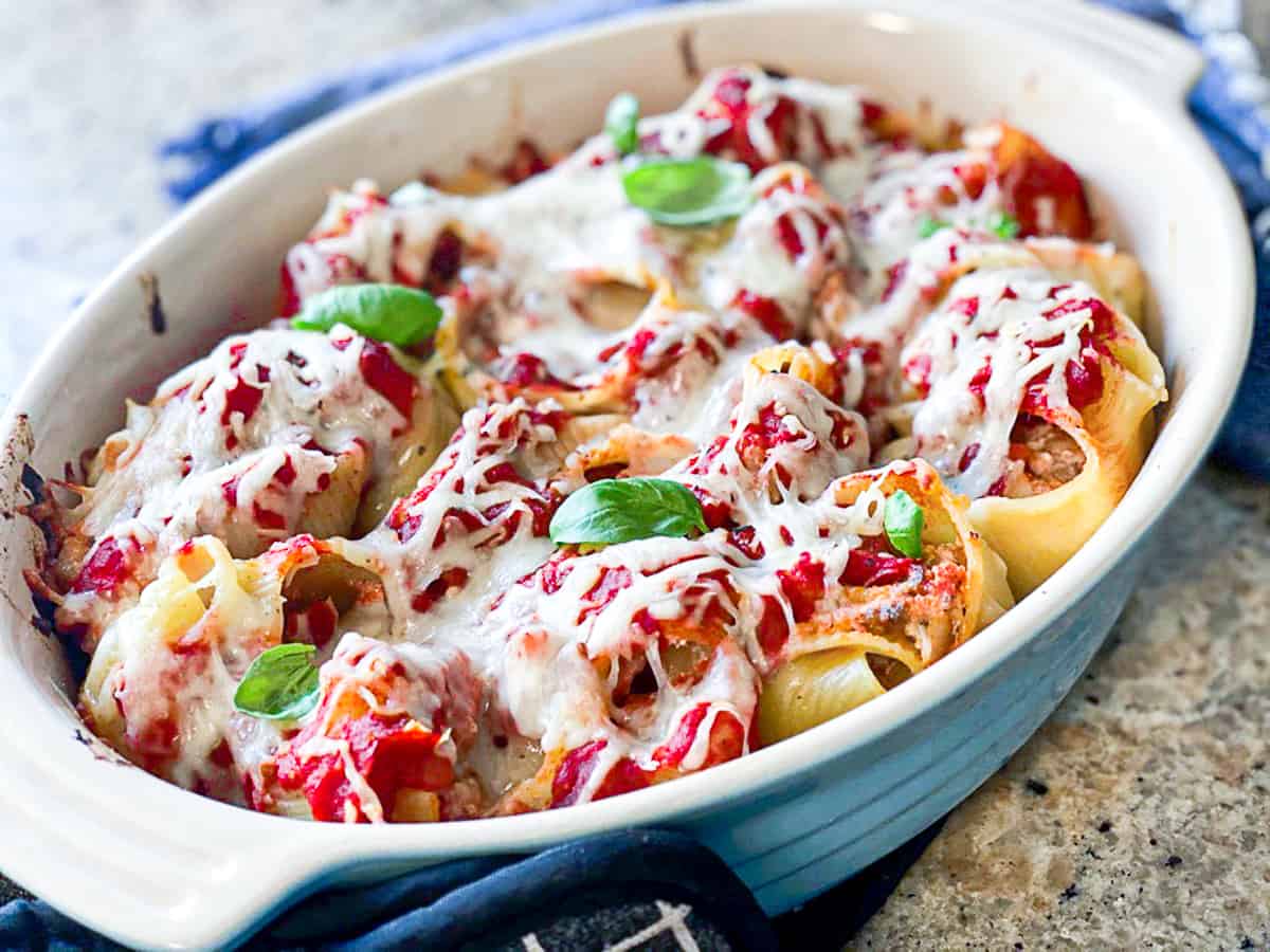Side shot of baked stuffed shells recipe in a serving dish.
