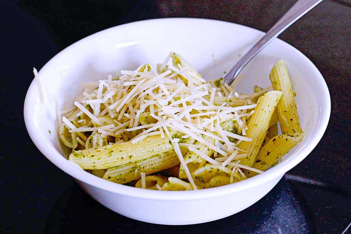 Side shot of pesto pasta with parmesan in a bowl.