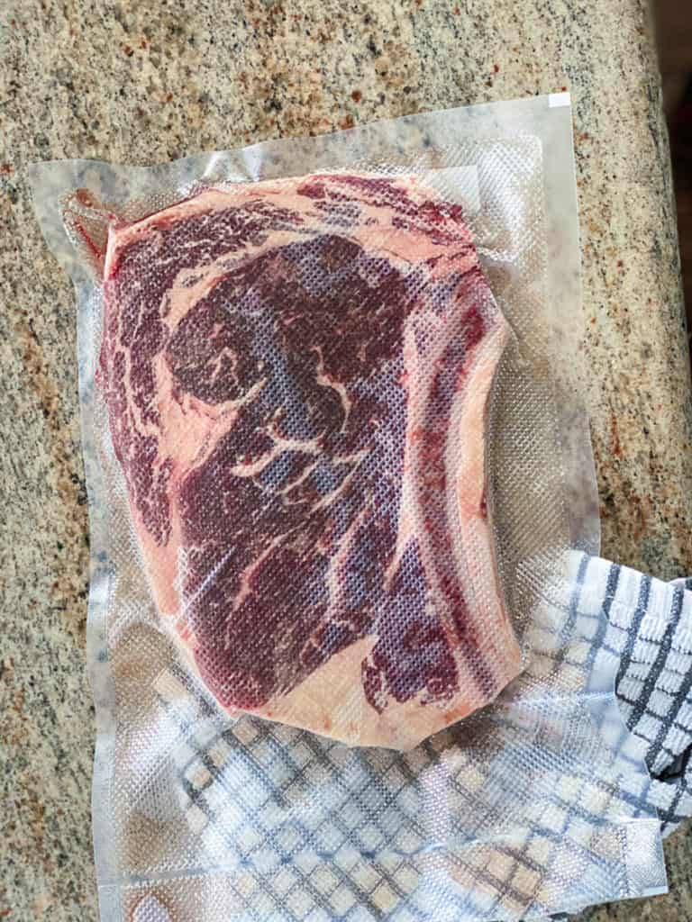 Top down shot of vacuum sealed ribeye steak in bag.