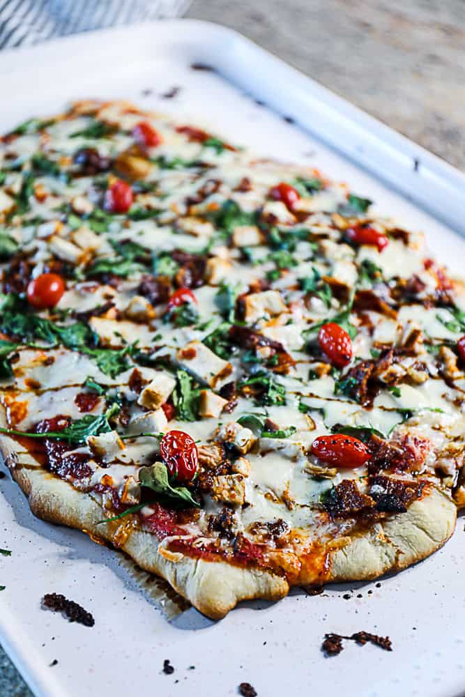 Side shot of homemade pizza with spinach and tomatoes.