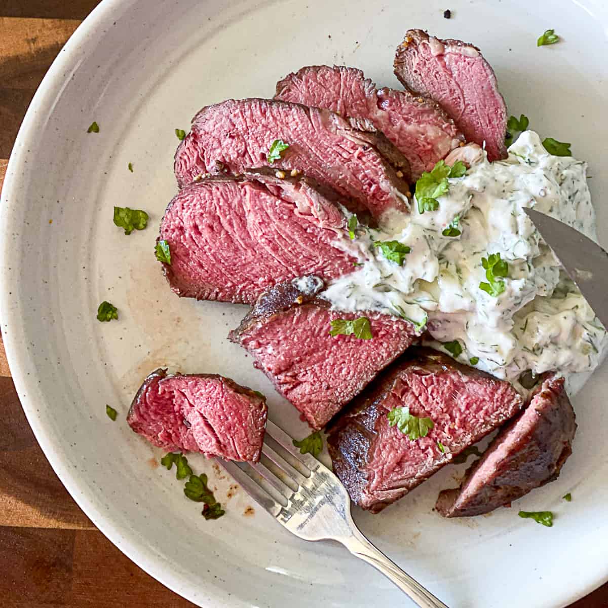 Medium rare, sous vide steak on white plate.