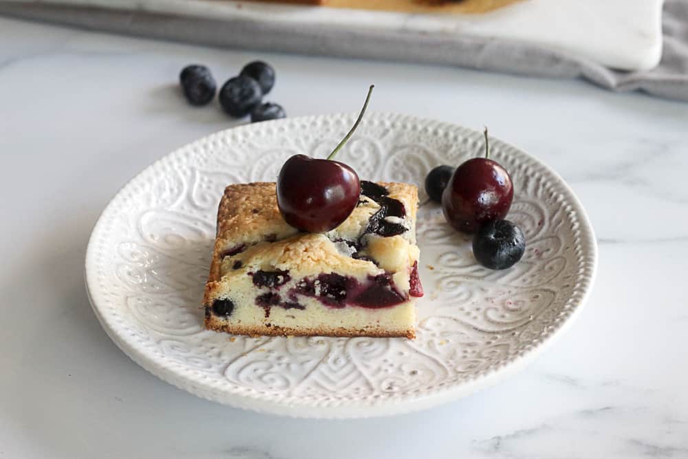 Side shot of cherry and blueberry cake on a dish.