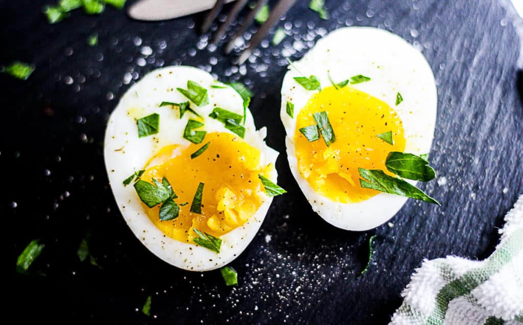 Closeup of sous vide boiled egg cut in half with herbs.