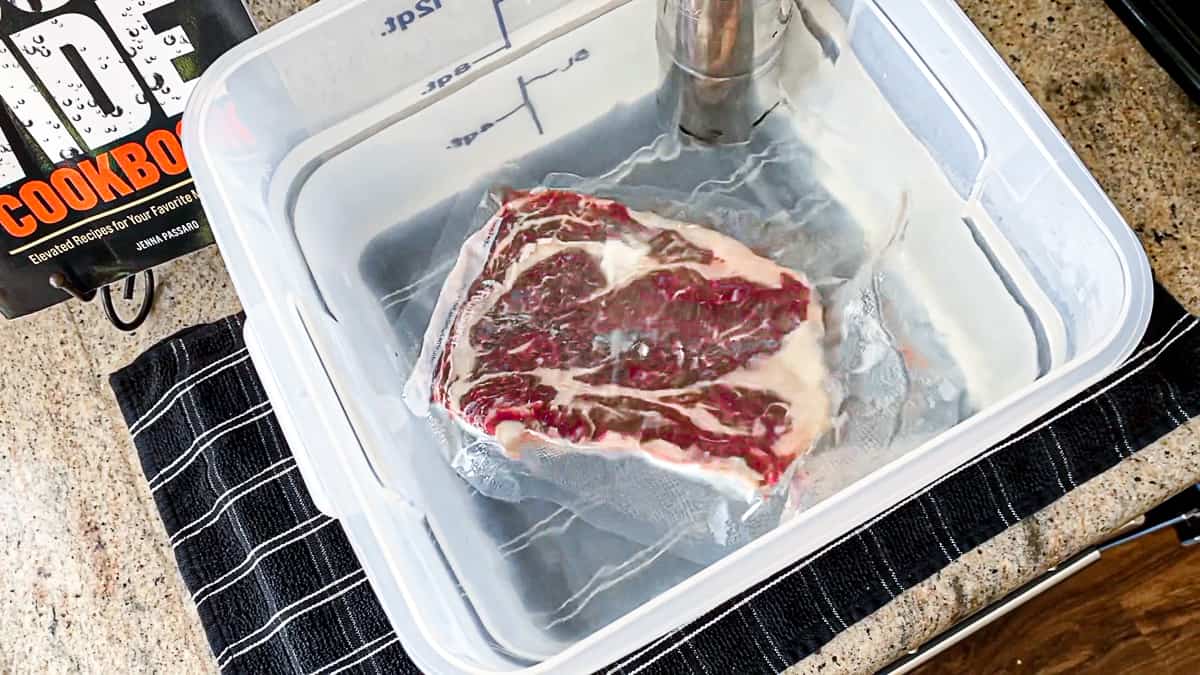 Top down shot of sous vide cooking seasoned steak in a water bath.