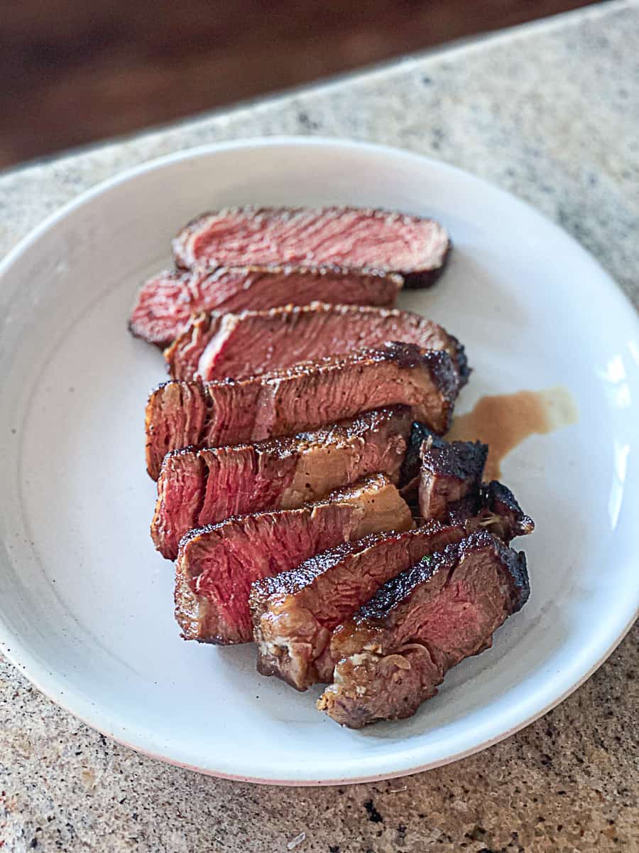 Top down shot of sous vide ribeye steak sliced on a plate.