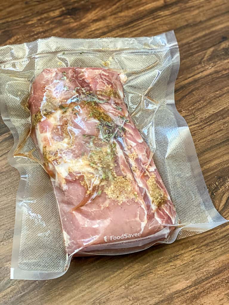 Top down shot of vacuum sealed sous vide pork loin with spices garlic and rosemary.