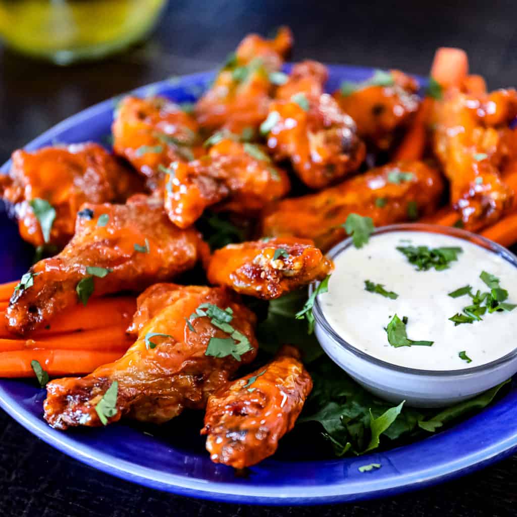 Side shot of Air Fryer Chicken Wings served on a party plate with blue cheese dressing.