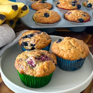 Closeup of banana blueberry muffins with frozen blueberries and raspberries.