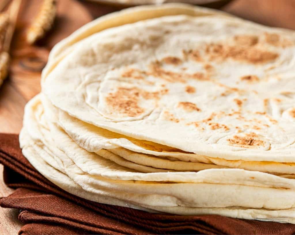 Side shot of flour tortilla stack on a table.