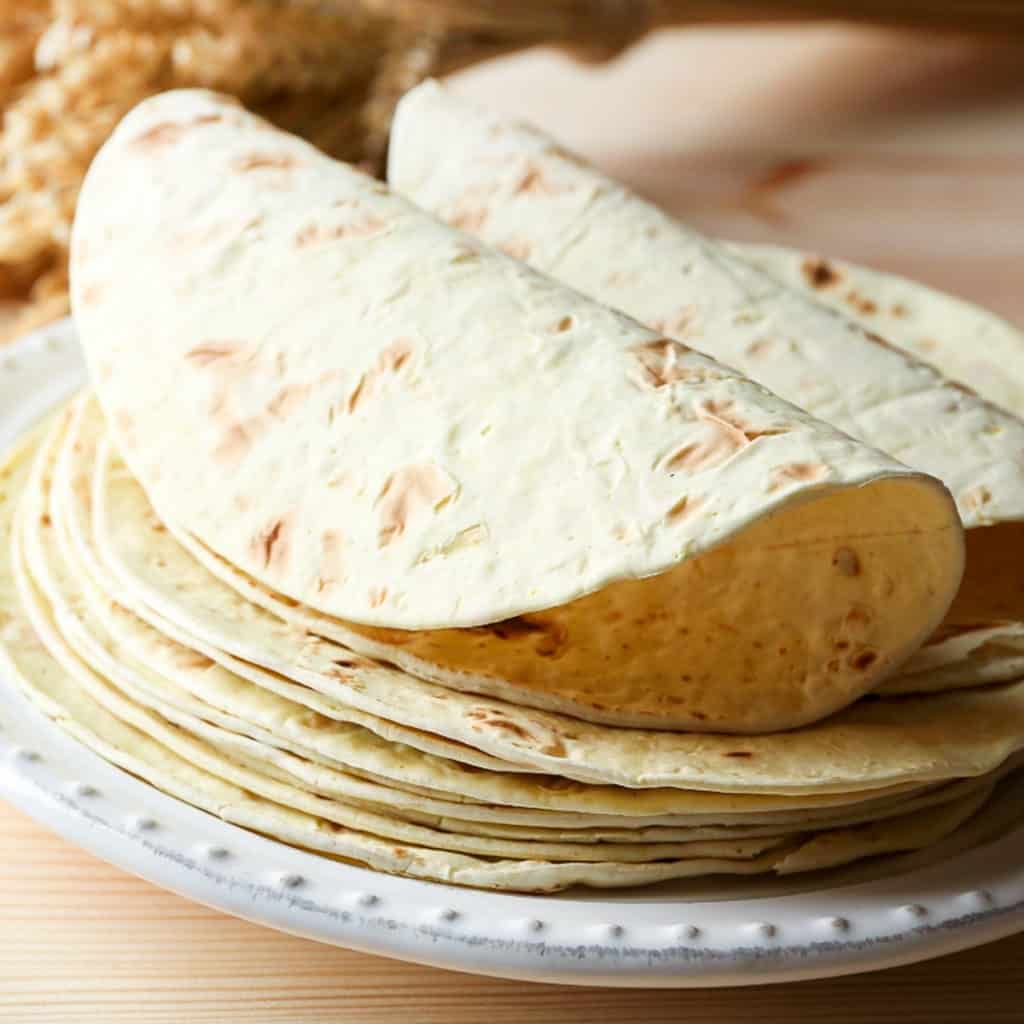 Side shot demonstrating thawed from frozen flour tortillas on a plate.