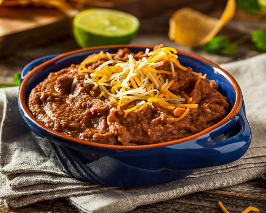 Bowl of refried bean dip with cheddar cheese.