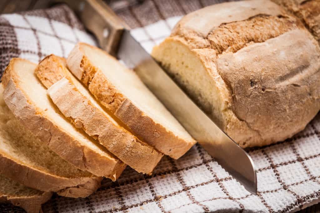 Side shot of knife slicing homemade bread