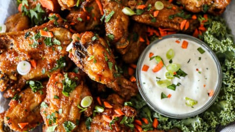 Top down shot of crispy baked chicken wings with blue cheese dressing on a party platter.