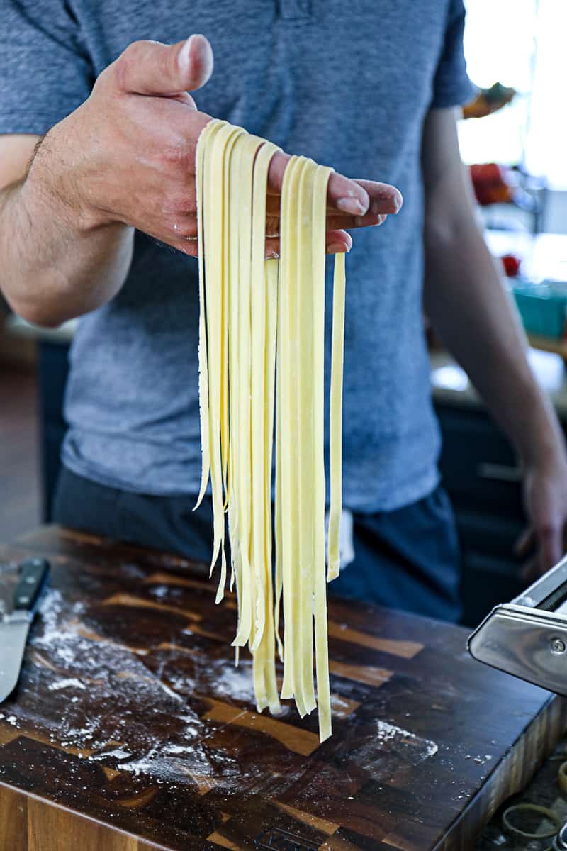 https://sipbitego.com/wp-content/uploads/2021/05/Homemade-Pasta-Recipe-Fettuccine-Linguine-Spaghetti-Sip-Bite-Go-side-shot-of-hand-holding-fresh-handmade-pasta-noodles-cut-to-fettuccine-shape.jpg