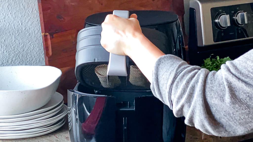 Side shot demonstrating how to add air fryer basket to phillips xl air fryer machine.