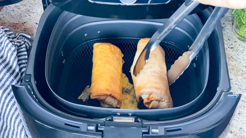 Top down shot demonstrating how to flip air fryer food during cooking process with tongs.