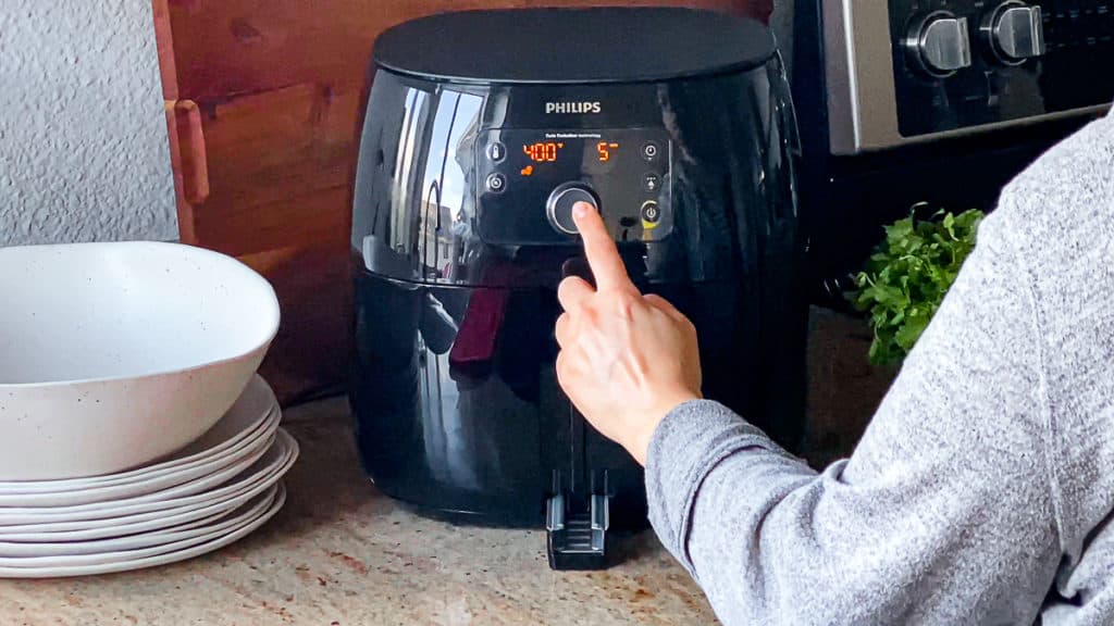 Side shot with hand demonstrating how to turn on air frying function on phillips xl air fryer machine.