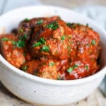 Closeup shot of keto friendly beef meatballs with fresh parsley in a bowl.