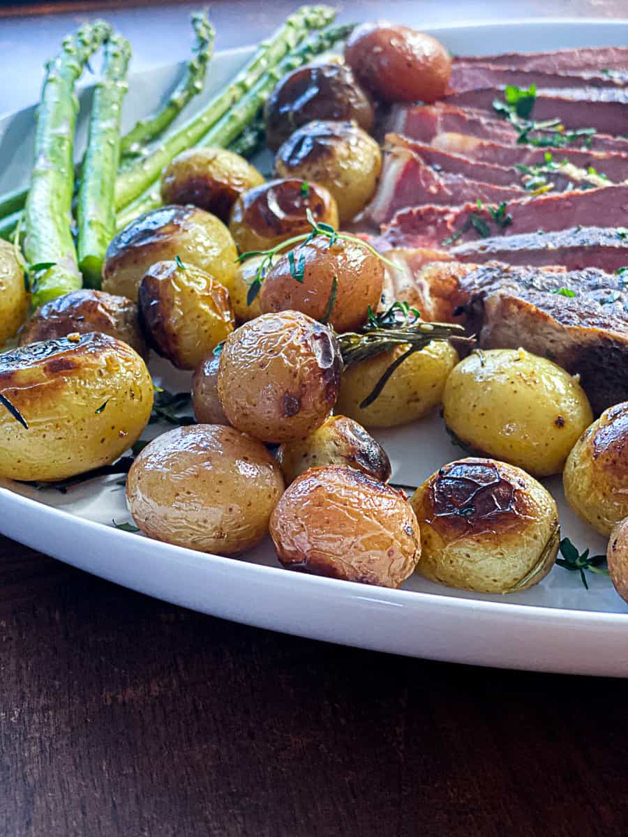 Side shot of crispy Sous Vide Little Potatoes with steak on a plate.