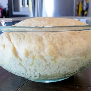 Closeup shot of homemade pizza dough recipe rising in a glass bowl.