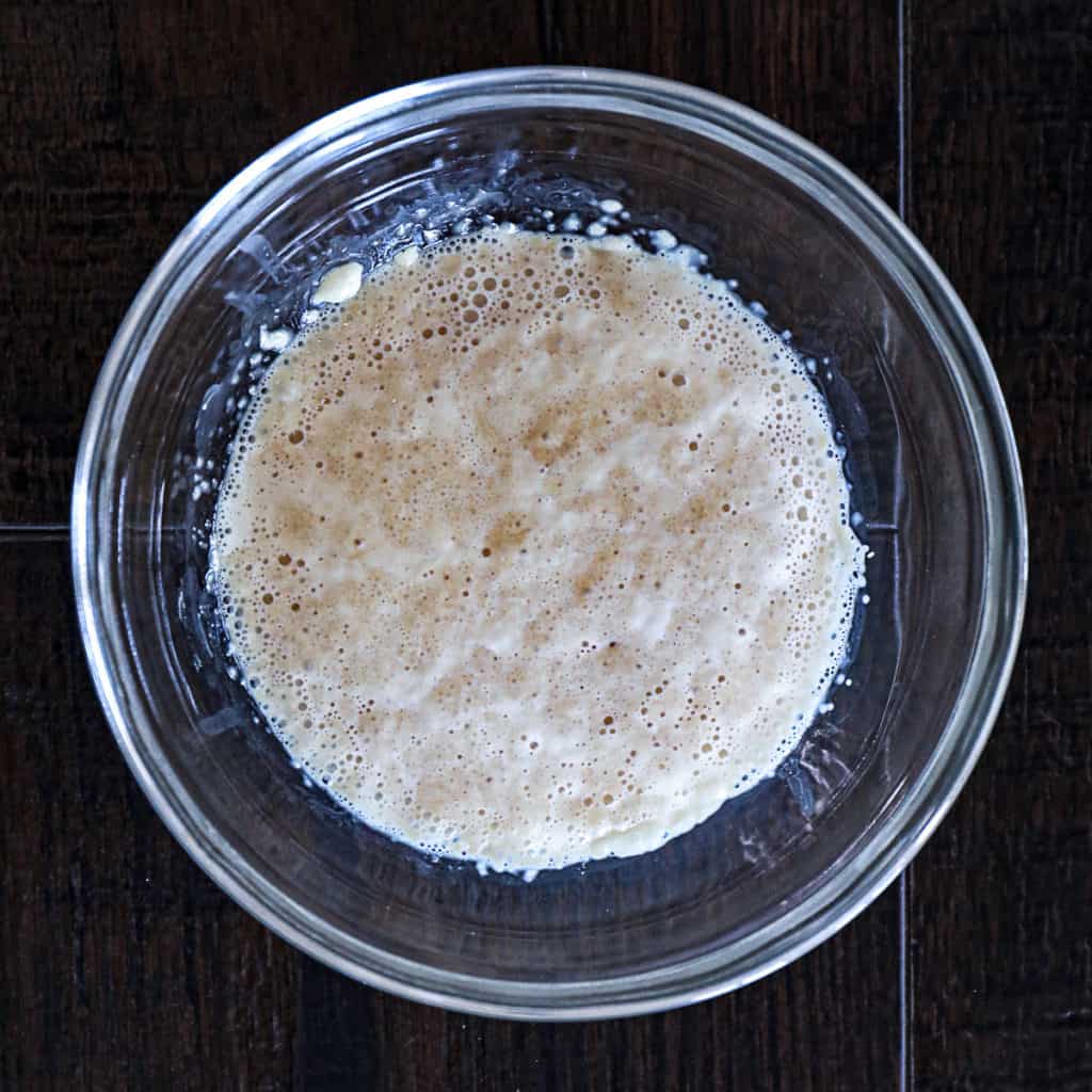 Top down shot of active yeast for pizza dough bubbling in warm water with sugar.