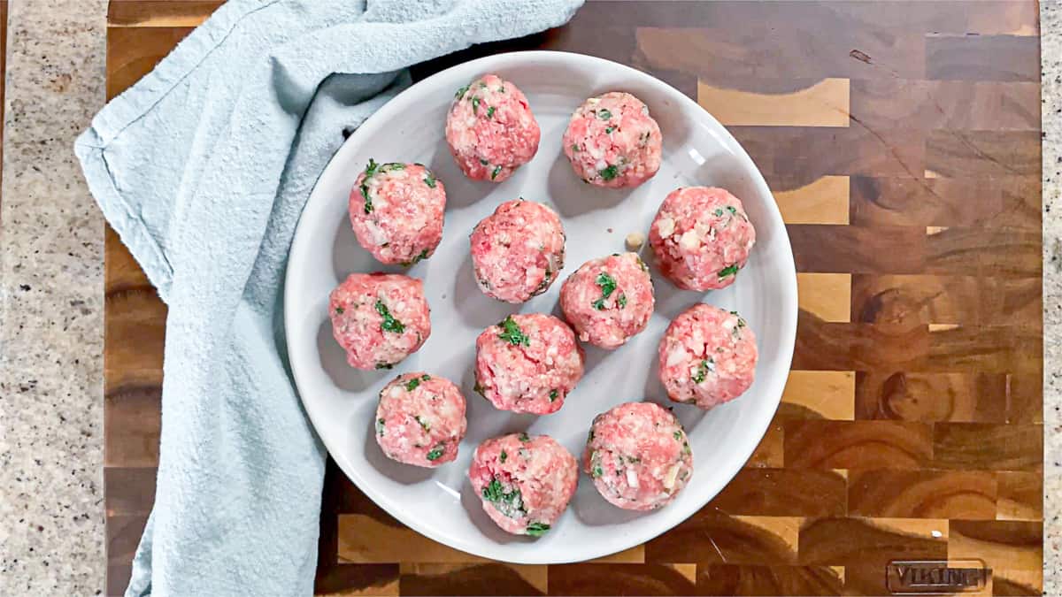 Top down shot of raw shaped meatballs on a plate.