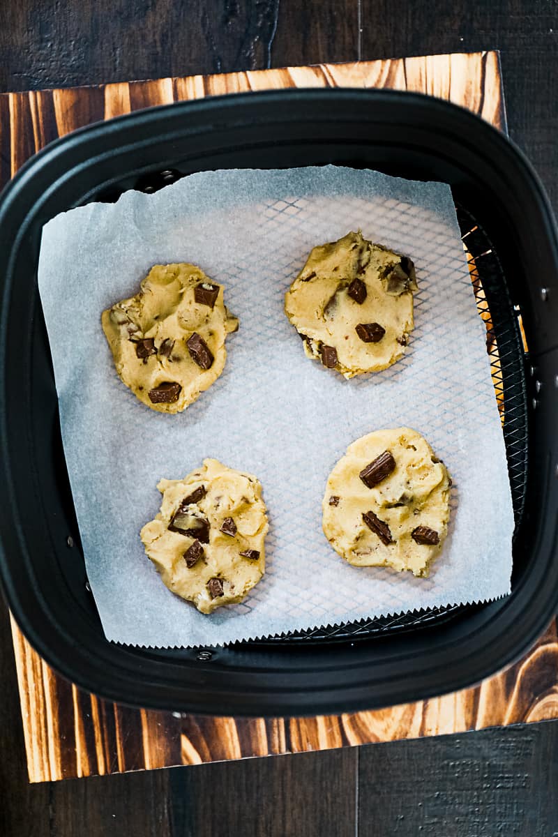 https://sipbitego.com/wp-content/uploads/2021/06/Air-Fryer-Chocolate-Chip-Cookies-Sip-Bite-Go-chocolate-chip-cookie-dough-smooshed-down-into-cookie-shape-on-a-piece-of-parchment-in-an-air-fryer-basket42.jpg