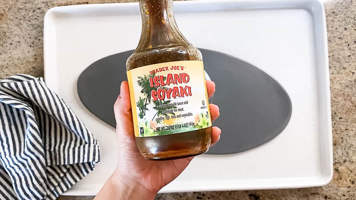 Top down shot of Hand holding Soyaki Teriyaki sauce from Trader Joe's.