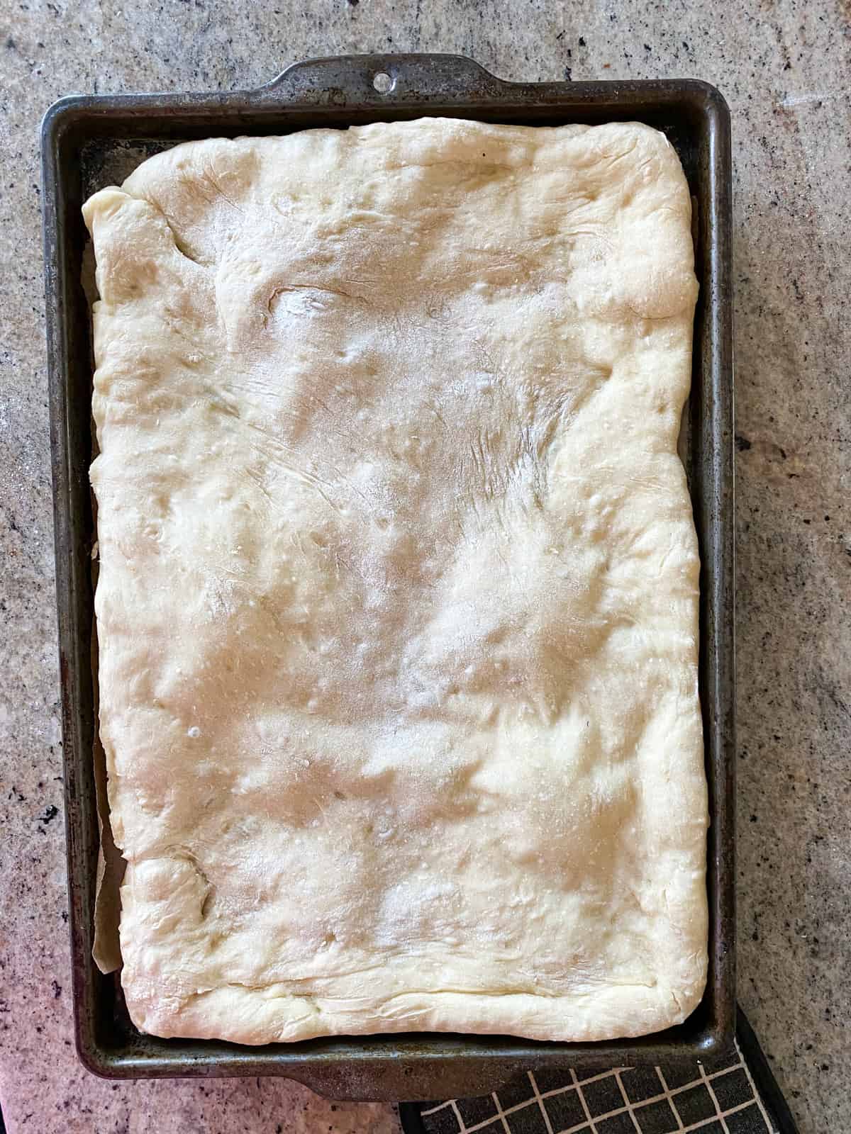 Top down shot of parbaked pizza crust on a sheet pan.