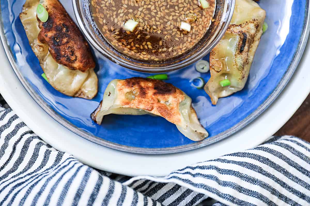 Top down shot of Trader Joe's gyozas and teriyaki sauce on a plate.