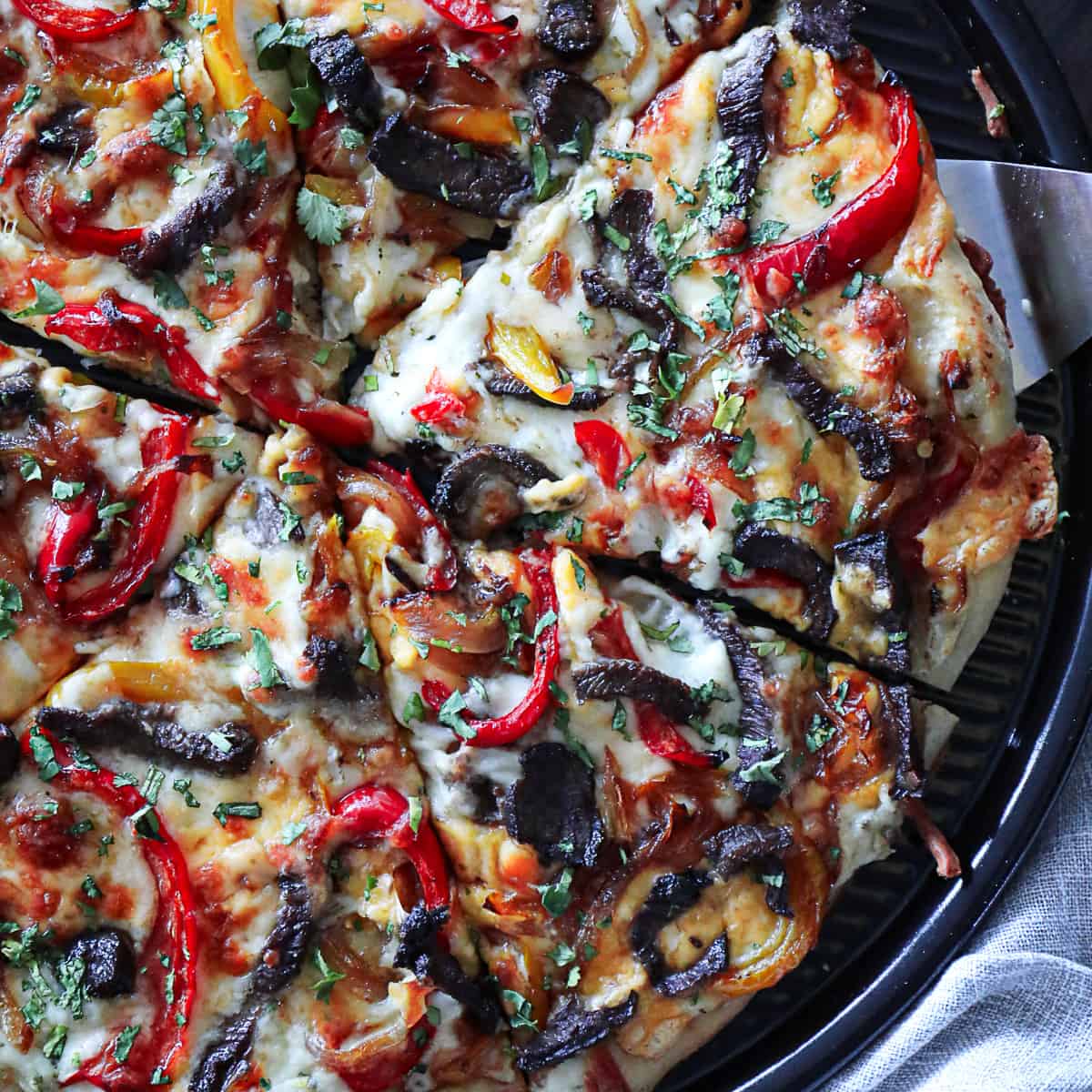 Closeup shot of Philly Cheese Steak Pizza Recipe with beef, bell peppers, onions, and cheese.