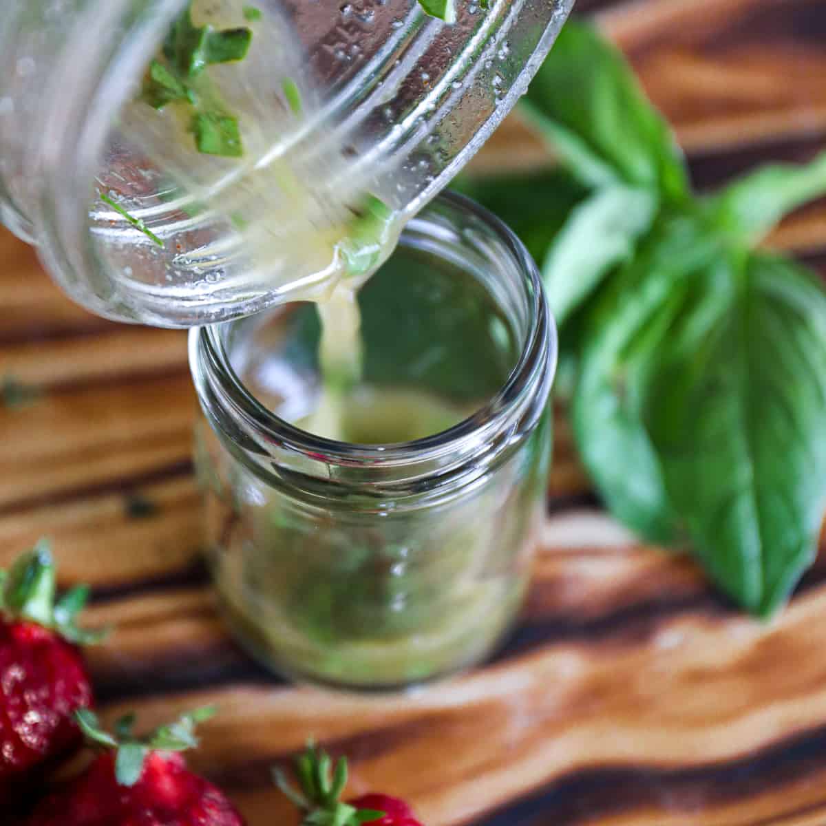 Pouring Honey Lemon Basil Dressing in a salad dressing jar.