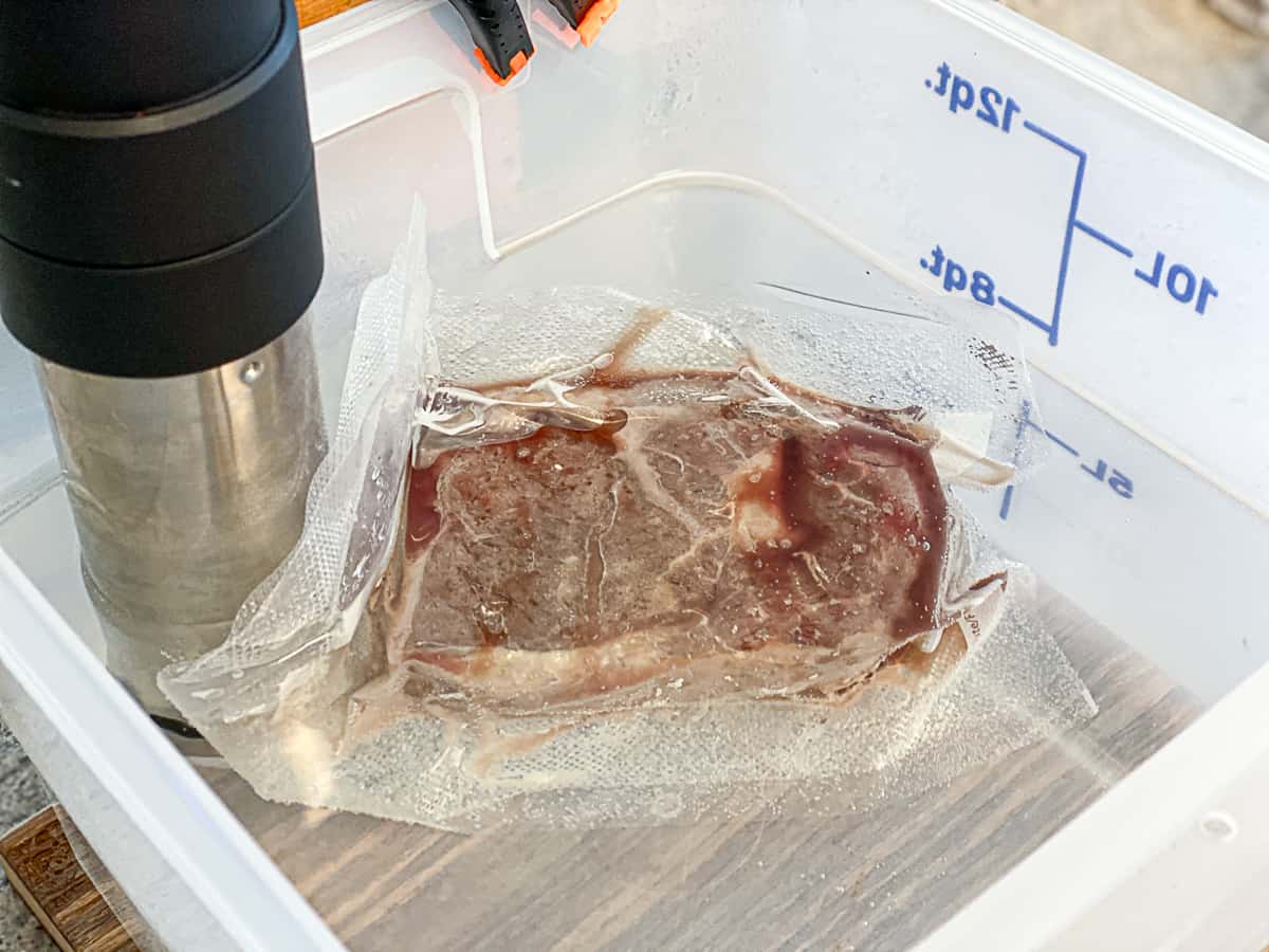 Side shot Sous viding steak in a water bucket.