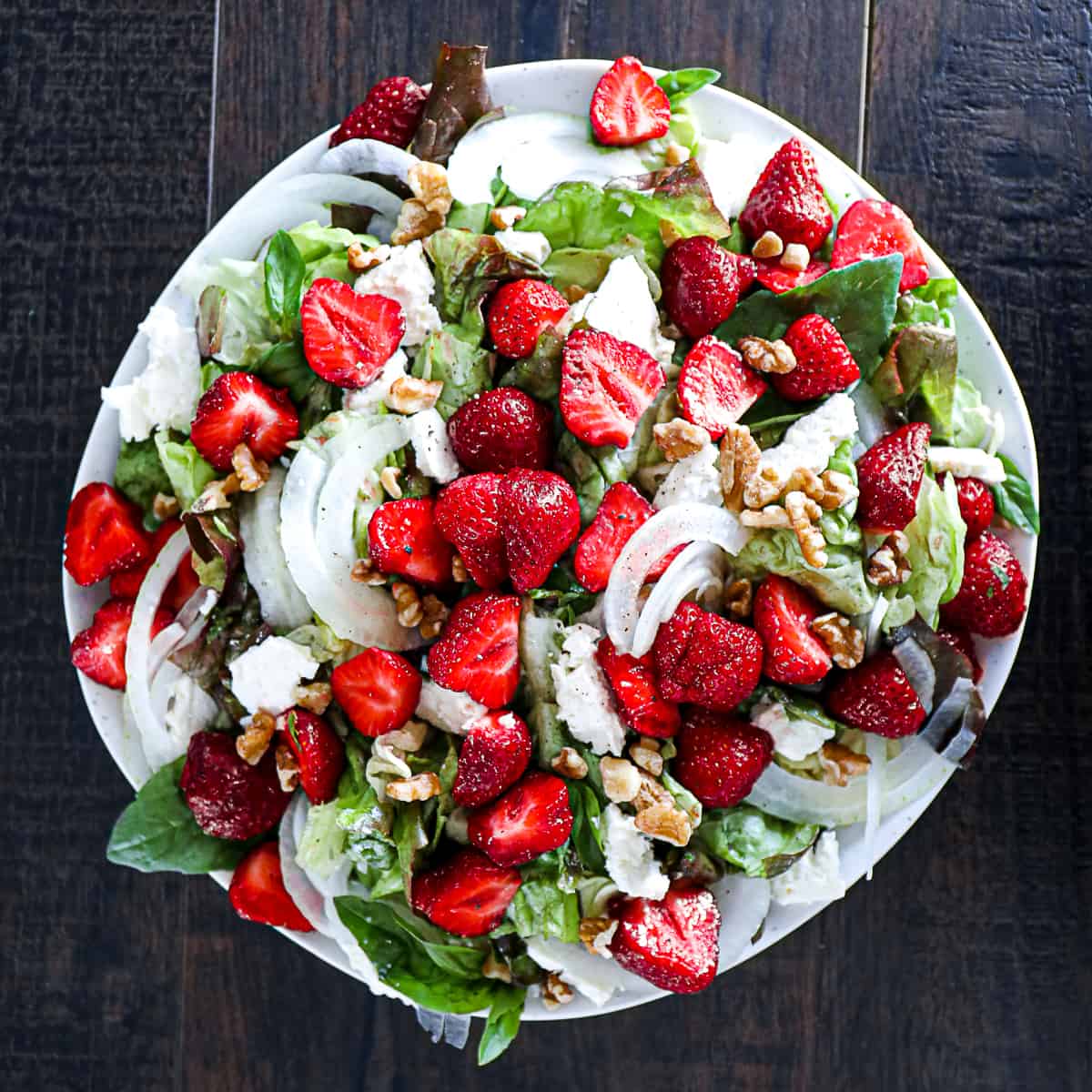 Top down shot of Strawberry Feta Salad With Walnuts and Basil Dressing on a plate.