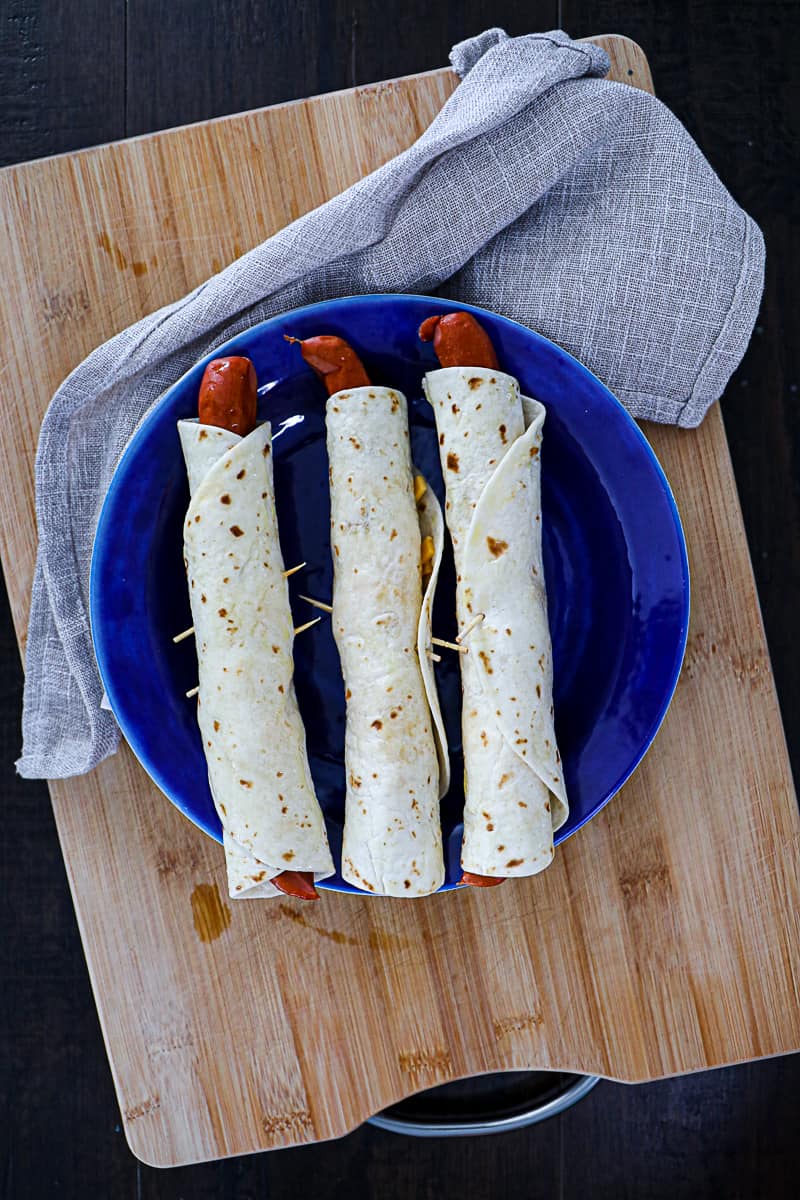 Tortilla wrapped hot dogs with cheddar cheese.