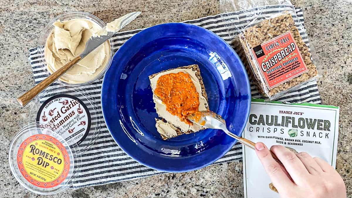 Top down shot of vegan trader joe's gluten free snacks idea with premade humus and crackers.