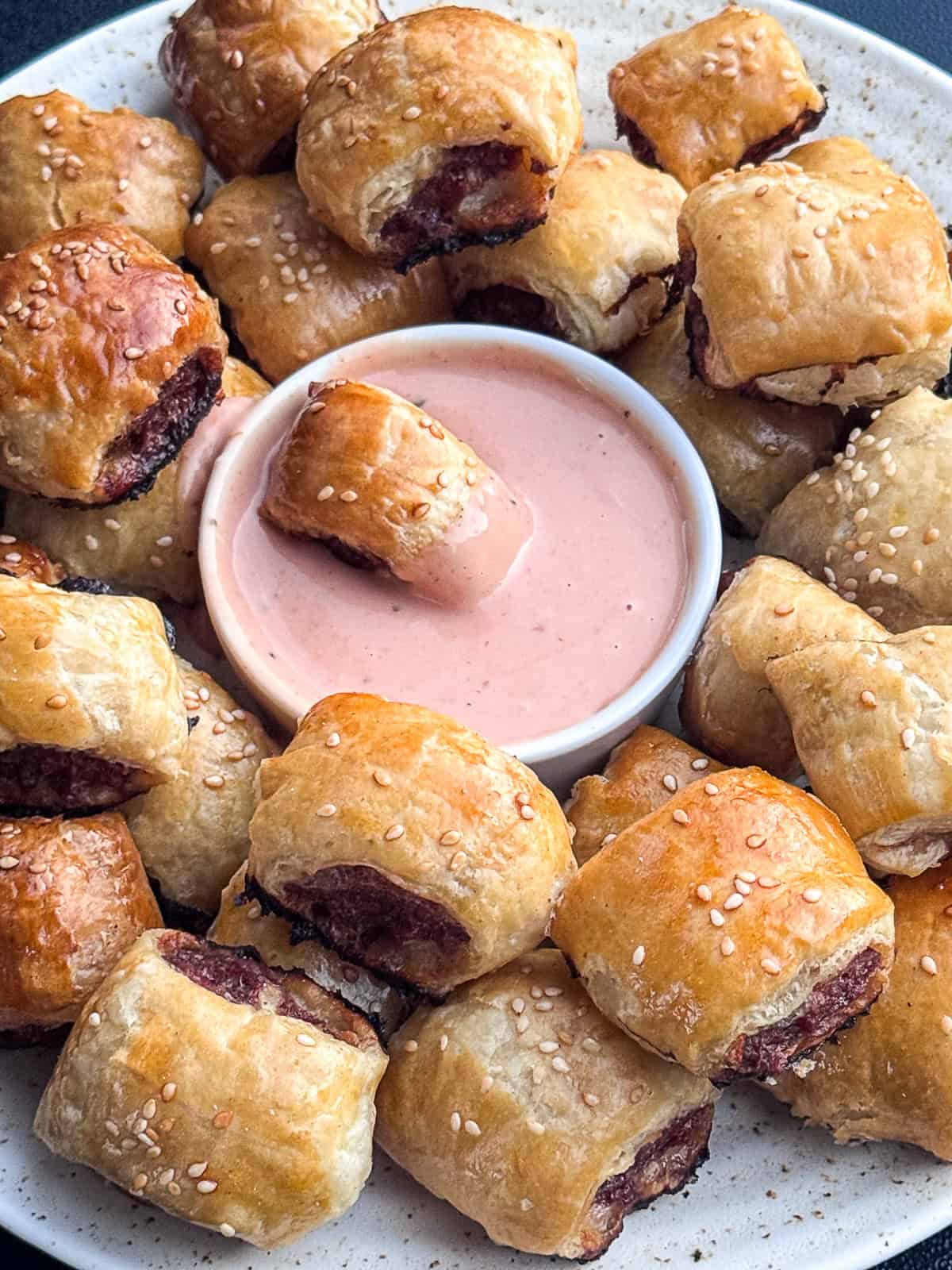 Burger Puff Pastry Bites Mini beef burgers wrapped in golden puff pastry served on a platter