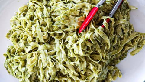 Fettuccine Pesto Pasta Recipe on a family style dinner serving platter with tongs.
