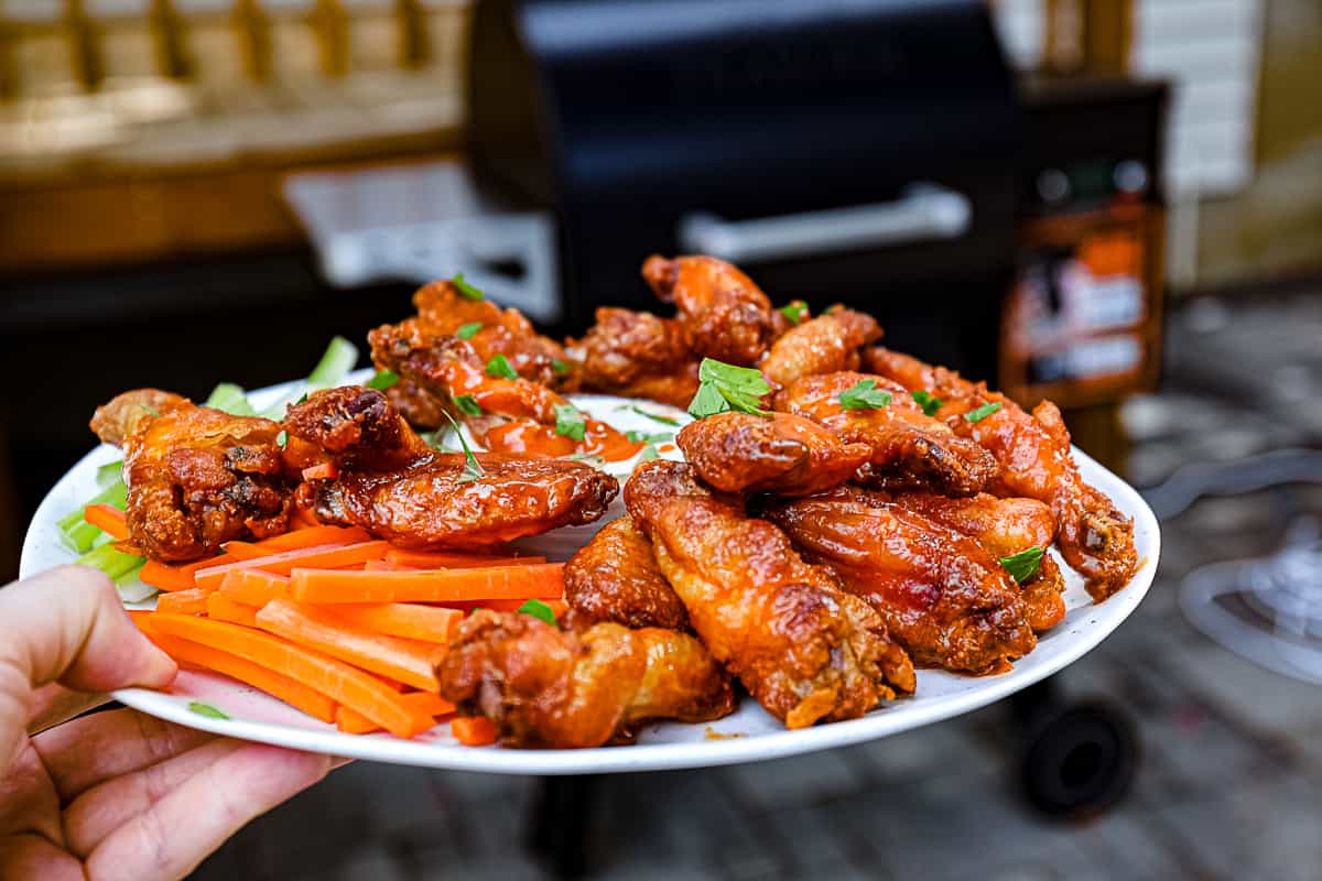 Smoked Chicken Wings with Traeger pellet grill in background.