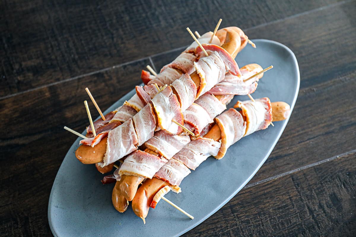 Assembled hot dog wrapped in bacon with toothpicks.