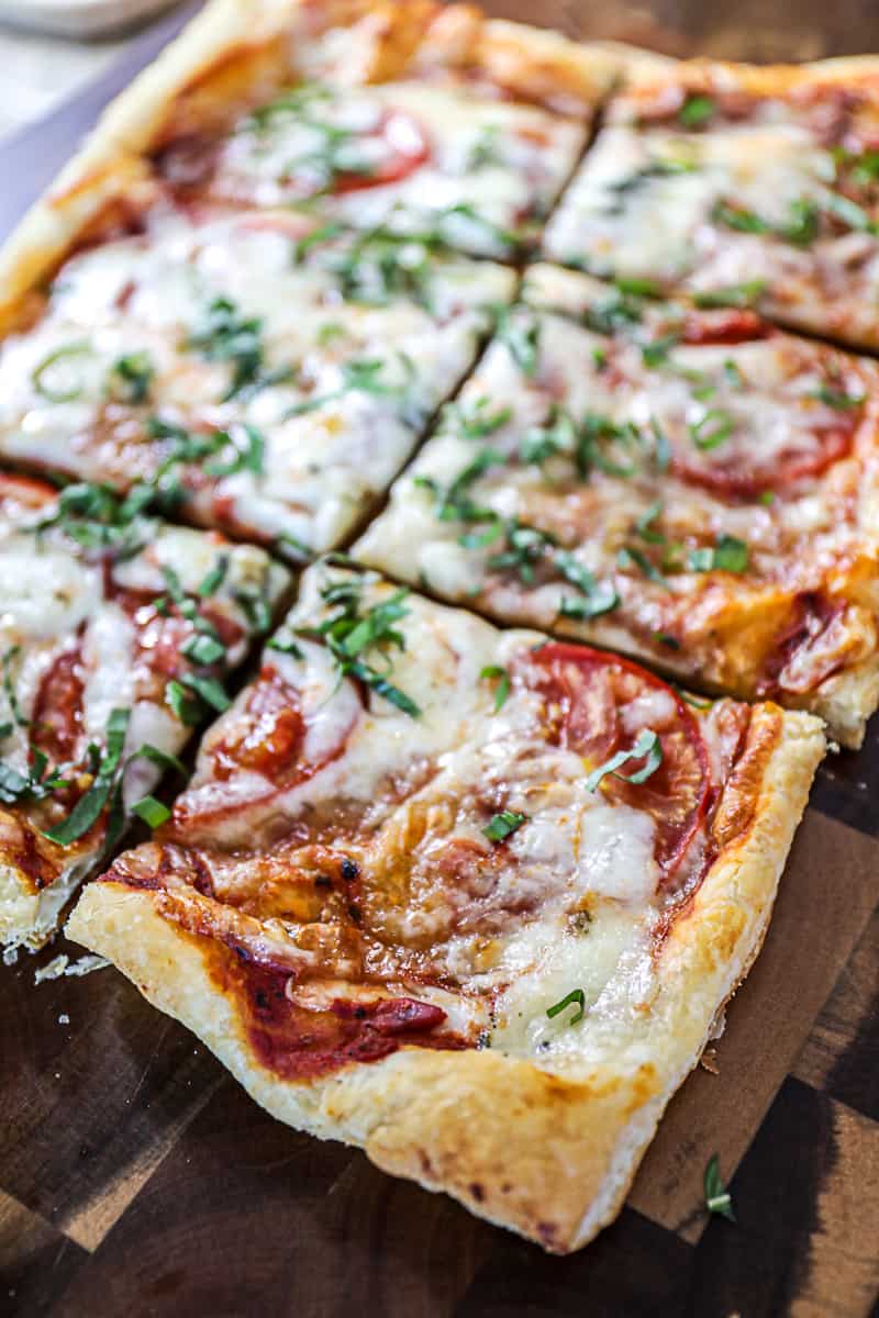 Closeup of flaky Puff Pastry Pizza with mozzarella cheese tomatoes and basil