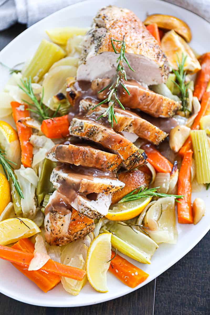 Oven roasted turkey breast with gravy and herbs on a platter.