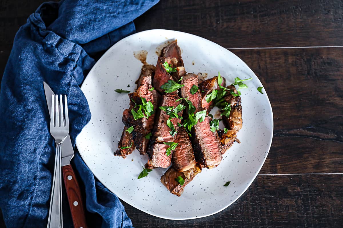Sliced T bone steak dinner idea on plate with silverware