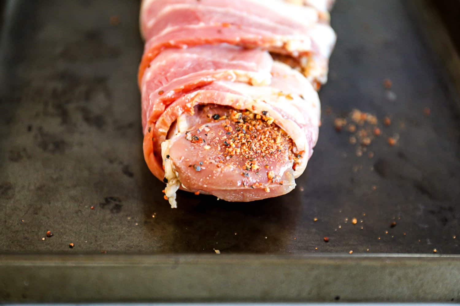 Closeup of pork tenderloin with silver skin removed wrapped in bacon