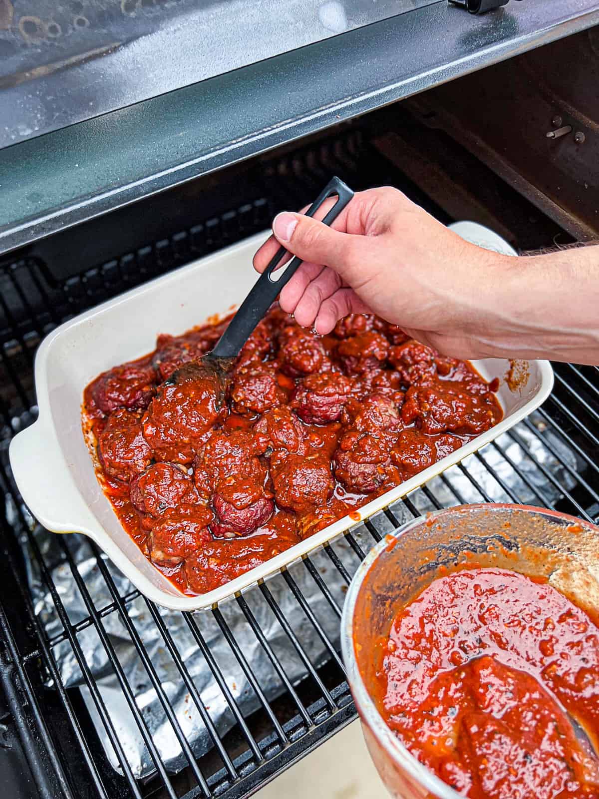 Adding pasta sauce to Traeger Meatballs smoked low and slow