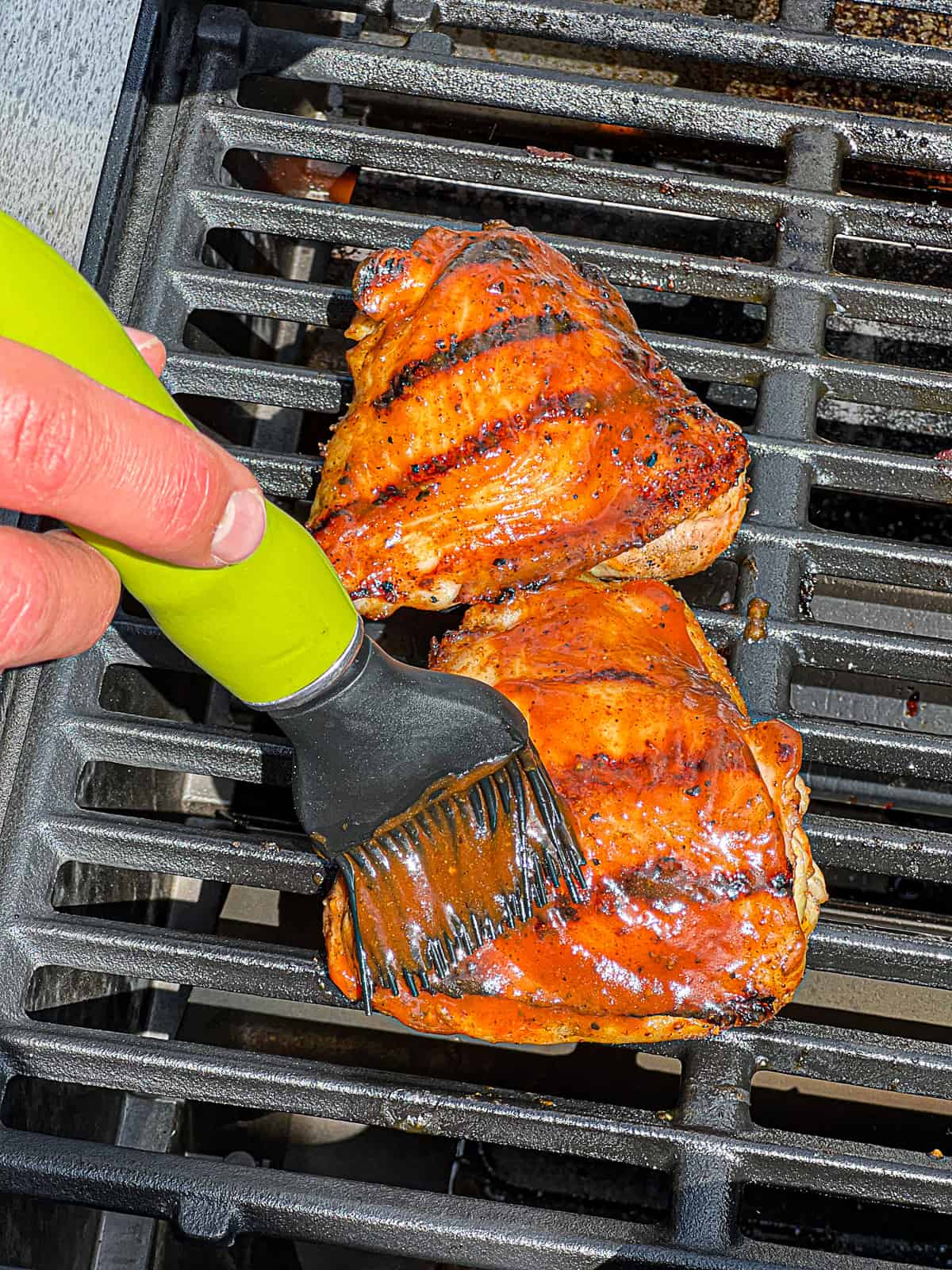 Closeup shot of Brushing BBQ Sauce On Grilled Chicken Thighs