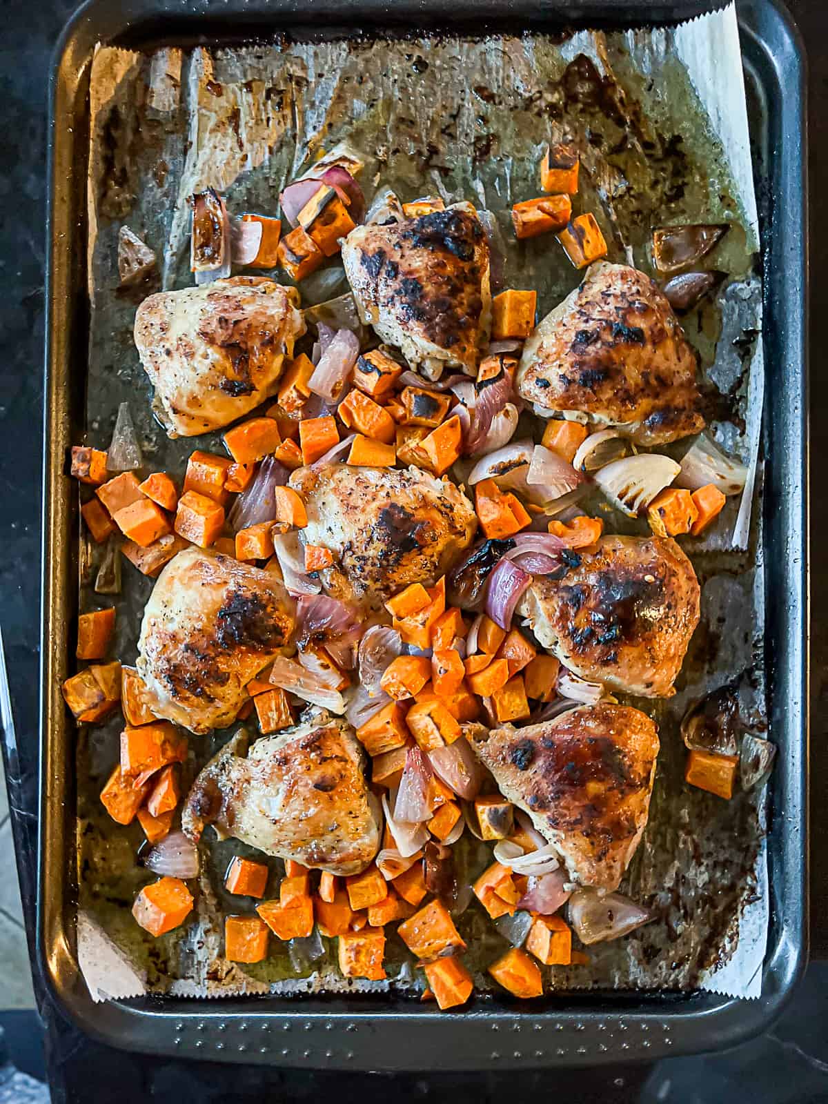 Parchment paper lined sheet pan meal with chicken thighs and potatoes